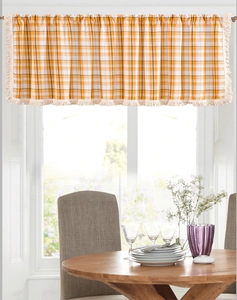 Detail of yellow and white plaid cafe curtain featuring decorative cream fringe tassels