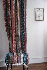 Detail of bohemian printed curtain with colorful stripes and white tassel trim