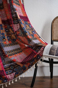 Detail of bohemian printed curtain featuring colorful patterns and white tassels on a chair