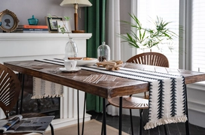 Detalle del camino de mesa tejido en blanco y negro con flechas geométricas y flecos