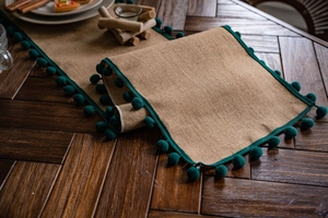 Texture détaillée du chemin de table en jute naturelle avec bordure à pompons verts