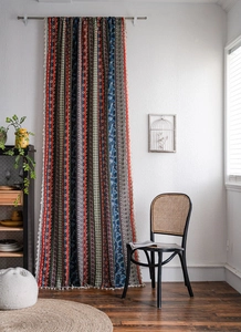 Detail of bohemian curtain with ethnic floral patterns and white decorative tassels