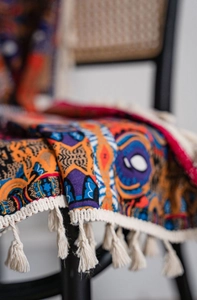 Detail of bohemian printed fabric with ethnic patterns and beige cotton tassels on chair