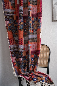 Detail of bohemian printed curtain fabric with colorful patterns and cream fringe trim