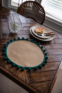 Gros plan détaillé d'un set de table en jute tressé avec pompons verts sur une table
