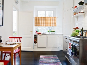 Detail of orange plaid cafe curtain with fringe trim hanging in a modern kitchen window