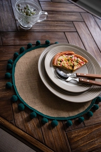 Vue de dessus du set de table en jute naturelle avec pompons verts sur table en bois