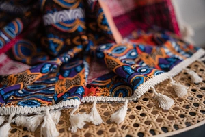 Detailed close-up of Bohemian printed fabric with ethnic patterns and cream fringe tassels