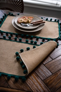 Détails de texture du chemin de table en jute naturelle avec bordure à pompons vert foncé