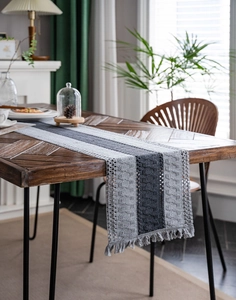 Close-up of gray cotton stripe table runner with woven texture and tassel details
