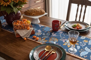 Détail du chemin de table jacquard aux motifs floraux orange et bleu de style vintage chic