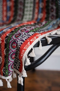 Detail of bohemian printed curtain with colorful geometric patterns and white fringe tassels