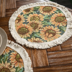 Round sunflower jacquard table mat with cotton fringes on a rustic dark wooden table