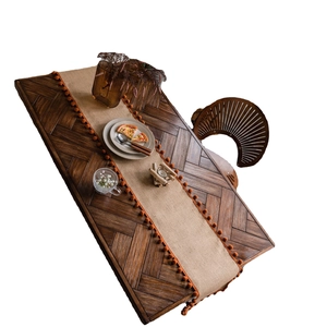 Natural jute table runner with bohemian orange pom pom trim on rustic wood table