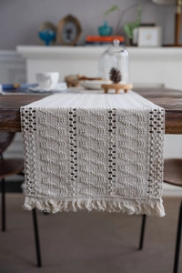 Detail showing hand-woven cotton table runner with fringe and geometric hollow patterns