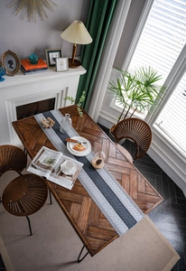 Close-up of herringbone wood dining table with grey striped woven table runner and tassels