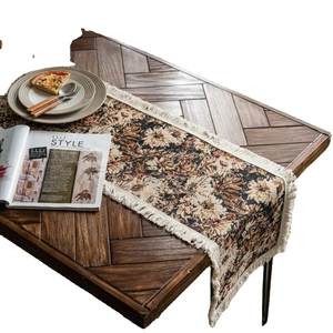 Vintage floral jacquard table runner with white fringe tassels on a dark wood table