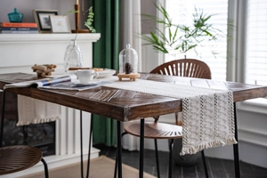 Close-up of beige woven table runner with hollow crochet patterns and tassel edges
