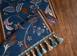 Détail du chemin de table en jacquard floral avec texture bleue et glands bicolores