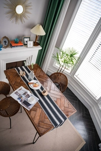 Gros plan du chemin de table tissé noir et blanc à motifs géométriques et gland