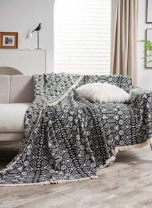 Detail of black and white geometric pattern sofa throw with decorative cream fringes