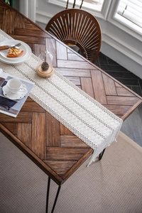 Close-up of bohemian woven table runner with hollow grid patterns and handmade tassels