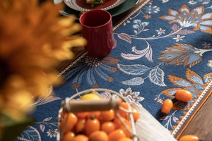 Détail du chemin de table jacquard avec motifs paisley orange et coutures blanches précises