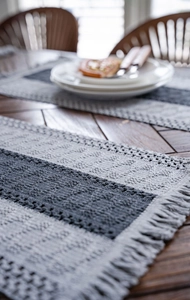 Close-up detail of grey and beige striped woven table runner with decorative tassels