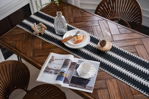 Détail d'un chemin de table tissé noir et blanc avec motifs tribaux sur table en bois