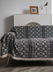 Detail of bohemian sofa cover with black and white geometric jacquard and cream fringe