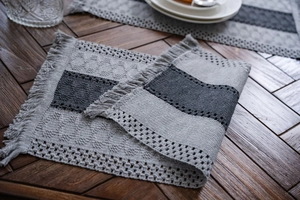 Detail of grey textured woven table runner with handmade fringe on a dark wooden table
