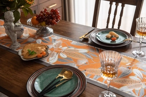 Close-up of floral jacquard table runner with orange and grey weaving on a dining table