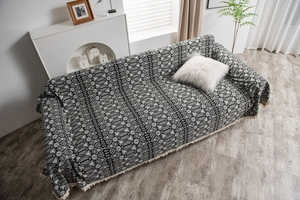 Detail of bohemian geometric jacquard throw blanket with handmade fringe tassels on sofa