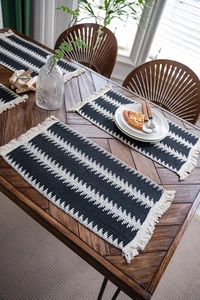 Gros plan des sets de table tissés noir et blanc avec franges sur table en bois