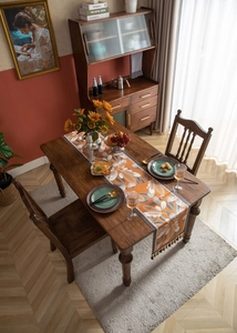 Detail view of jacquard table runner with orange floral pattern and decorative tassels
