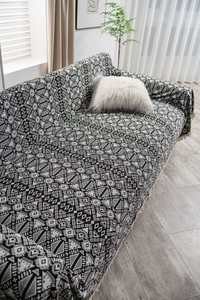 Detail of black and white geometric jacquard throw blanket with decorative fringe edges