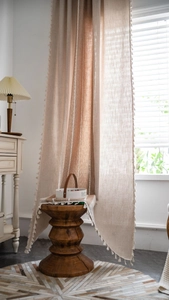 Detail of linen stripe curtain featuring rustic cotton ball fringe and woven texture