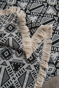 Close-up of black and white geometric jacquard pattern on sofa throw blanket with tassels
