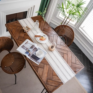 Minimalist white textured table runner with fringe on a herringbone walnut dining table