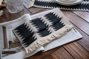 Détail d'un chemin de table tissé noir et blanc avec franges en coton et texture ondulée