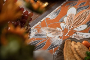 Detail of woven table runner featuring orange harvest patterns and floral textures