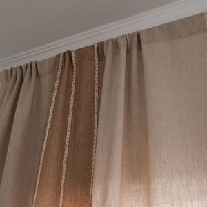 Neutral linen curtains with dark brown side stripes and white X-patterned embroidery
