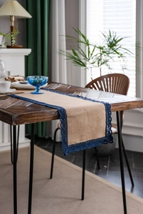 Detailopname van natuurlijke jute tafelloper met elegante marineblauwe kanten afwerking