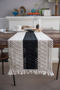 Detailed view of black and beige woven table runner with tassels and knit texture