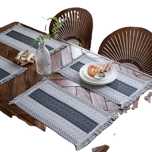Gray striped woven table mat with tassels on a wooden dining table in a cozy home setting