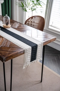 Detail of hand-woven table runner with dark gray stripes and cotton tassel fringe