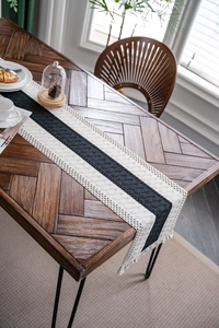 Close-up of black and white striped woven table runner with fringes on wooden table
