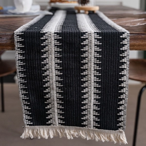 Chemin de table moderne à rayures noires et blanches avec pompons et texture tissée