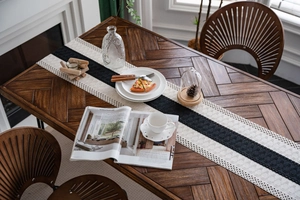 Detail of black and white striped woven table runner with boho crochet texture on wood