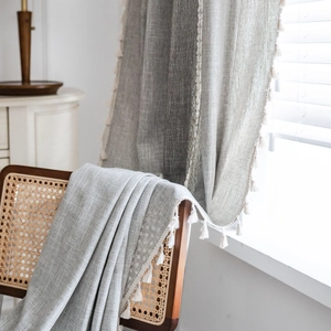 Grey linen curtain with decorative white tassels for a farmhouse style living room